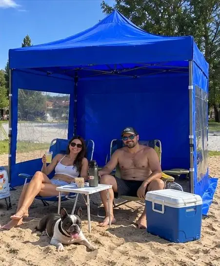 Pareja en la playa bajo un gazebo azul